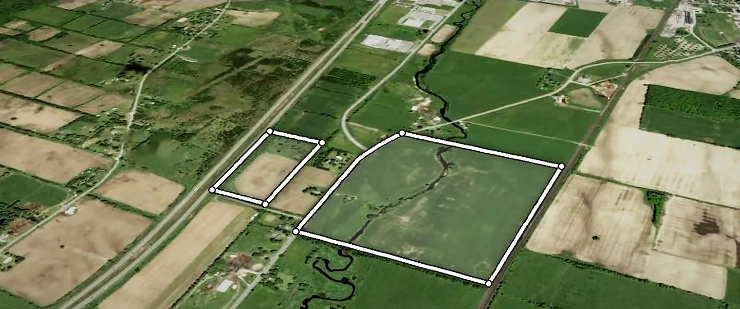 Aerial view looking northeast over both parcels: 18.3 acres on Highway 401 and 88.5 acres between County Road 1 and the CN rail line, with the creek crossing it